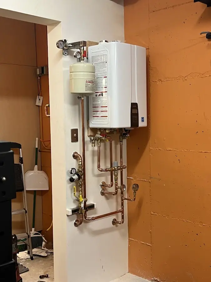 Plumbing technician inspecting water heater connections in Sterling Heights